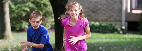 Photo of a boy and girl having a race in their yard.
